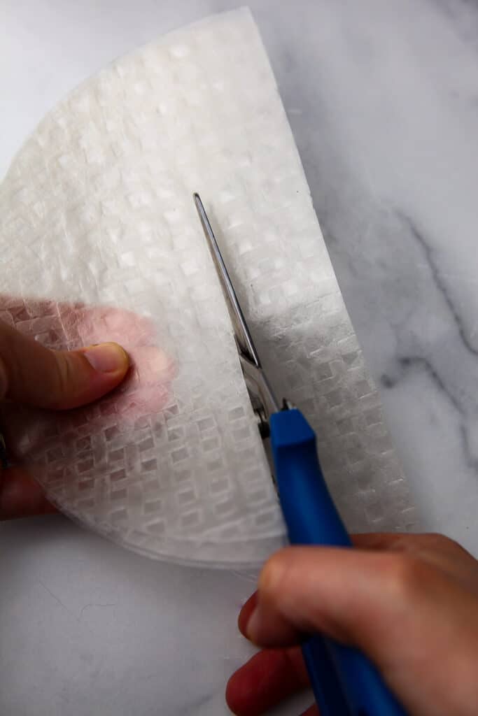 Hands cutting rice paper into strips to make vegan bacon with it.