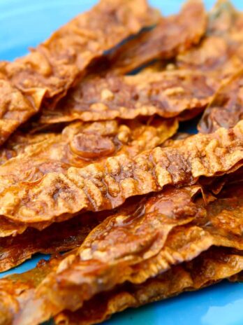 A pile of vegan bacon on a bright blue plate.