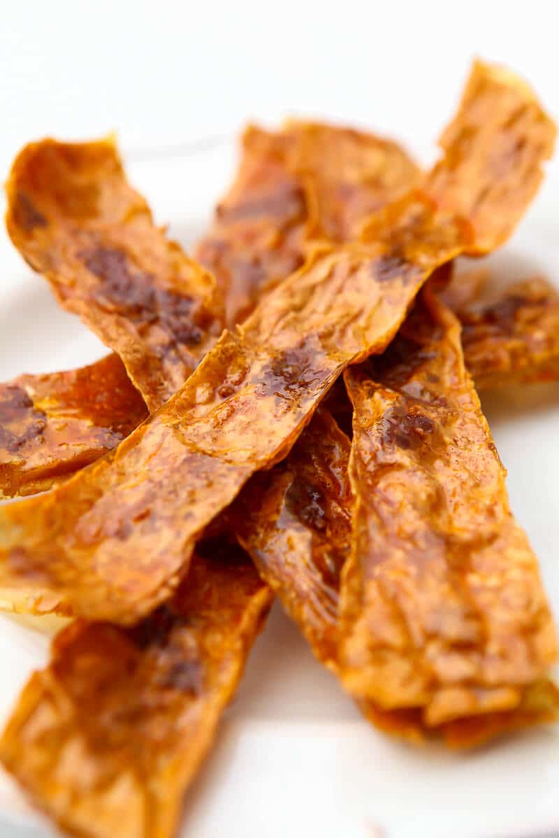 A white plate filled with vegan bacon made from rice paper and tofu.