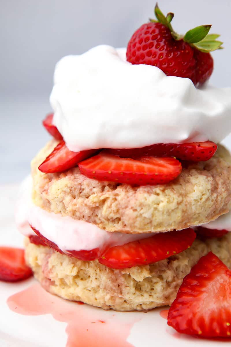 Vegan strawberry shortcake stacked with strawberries and vegan whipped cream on top and in between the layers.