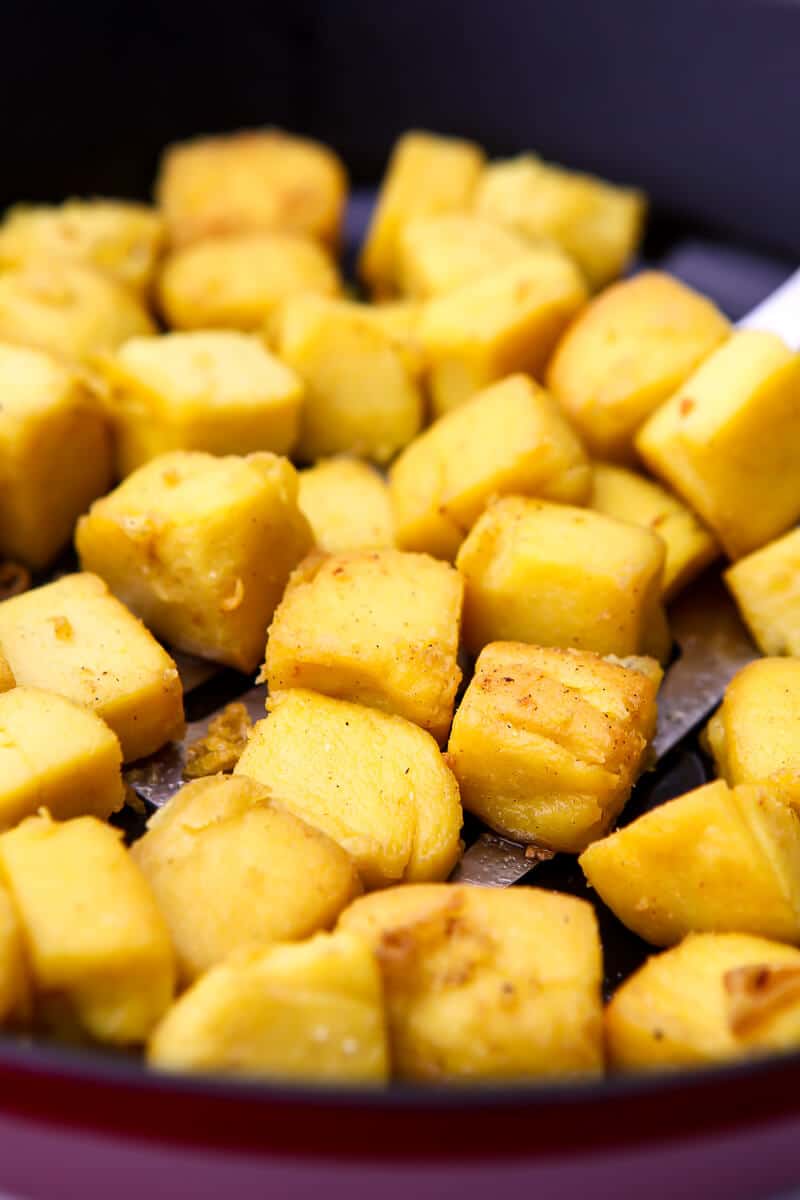 Chickpea tofu being fried in an iron skillet.