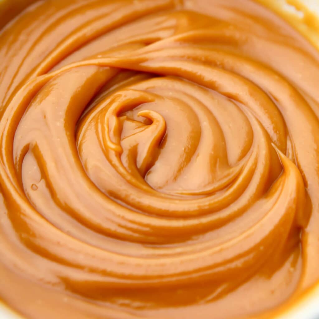 A close up of vegan peanut butter caramel dip swirled in a bowl.