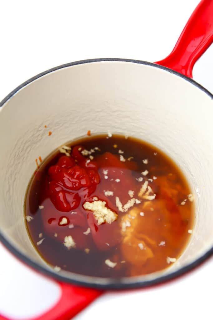 All of the ingredients for sweet and sour sauce in a red saucepan.