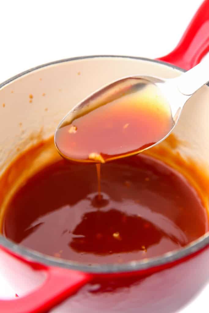 A small red sauce pan filled with vegan sweet and sour sauce.