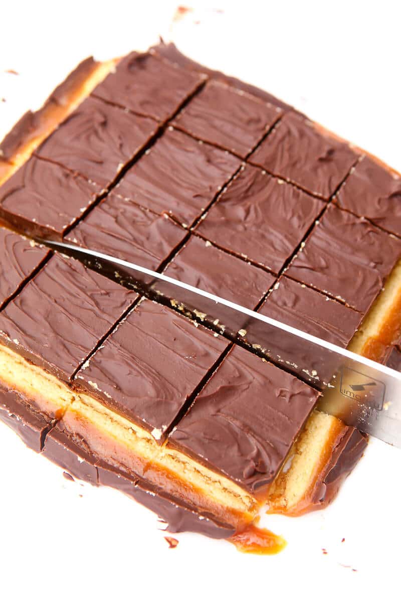 A large knife cutting millionaire shortbread into squares.