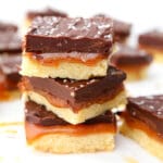 Three vegan millionaire shortbread bars stacked on top of each other.