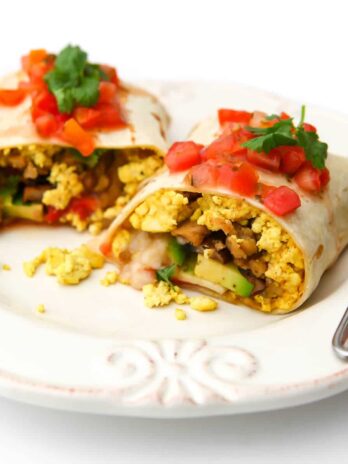 A vegan breakfast burrito cut in half with salsa and cilantro on top.