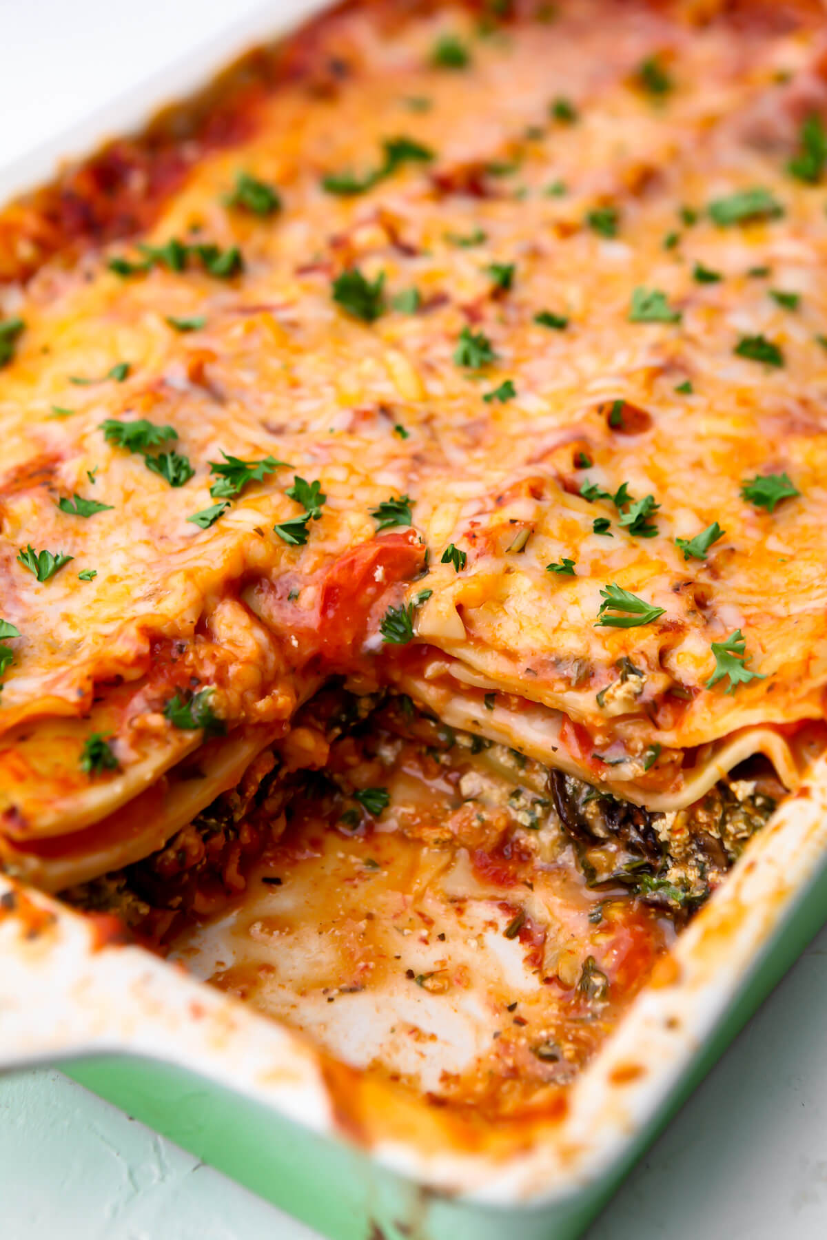 A pan of baked vegan lasagna with a piece taken out of it.