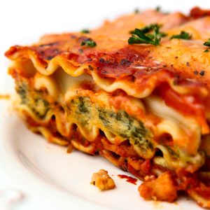 A close up of a piece of vegan lasagna with tofu spinach ricotta and TVP sausage.