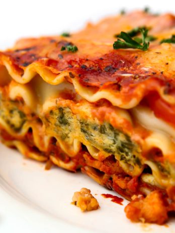 A close up of a piece of vegan lasagna with tofu spinach ricotta and TVP sausage.