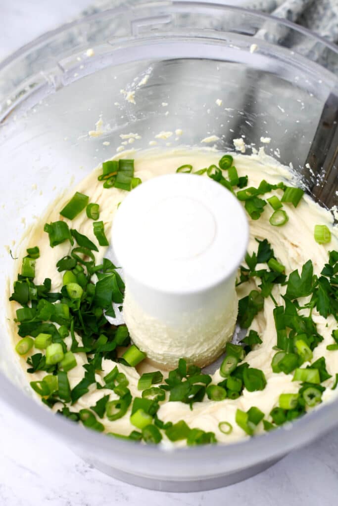 Vegan cream cheese with herbs added in a food processor.