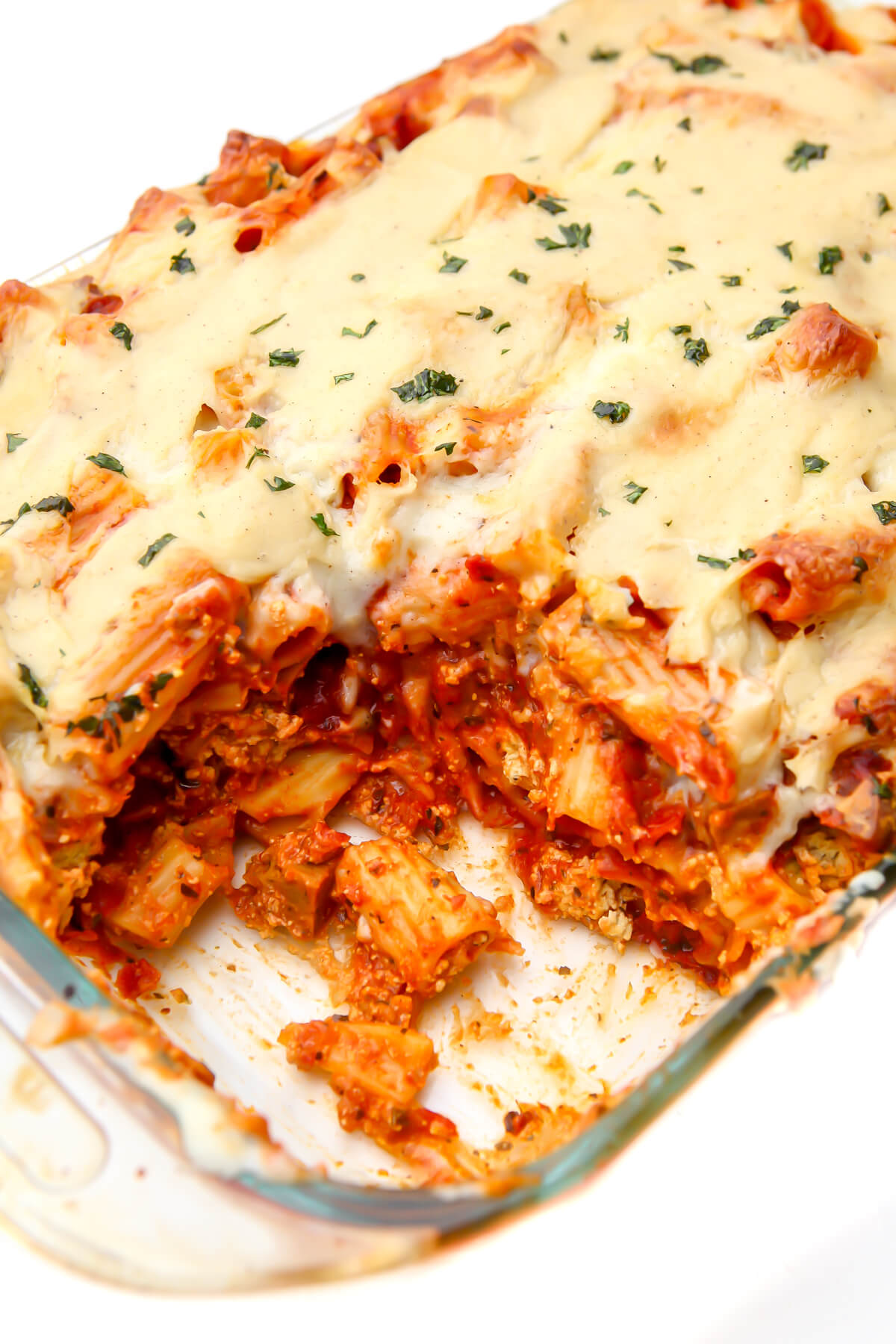 A casserole dish full of vegan baked ziti with a scoop taken out of it.