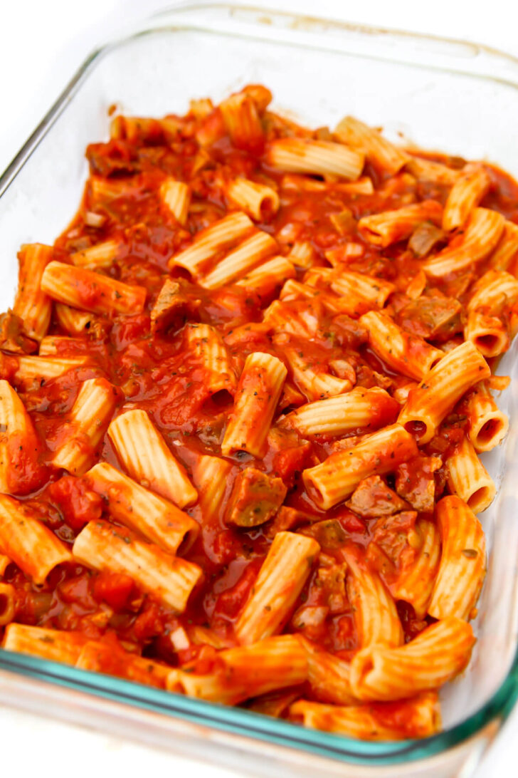 Ziti noodles and sauce added to the bottom of a baking dish.