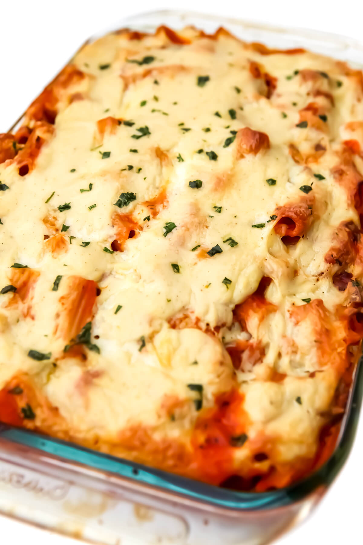 A baking dish filled with vegan baked ziti with vegan sausage, tofu ricotta, and topped with vegan béchamel.