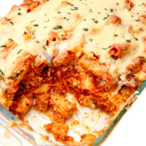 A casserole dish full of vegan baked ziti with tofu ricotta baked in and bechamel sauce on top.