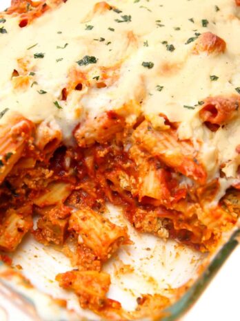 A casserole dish with vegan baked ziti with a scoop taken out of it.