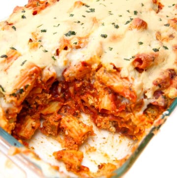 A casserole dish with vegan baked ziti with a scoop taken out of it.