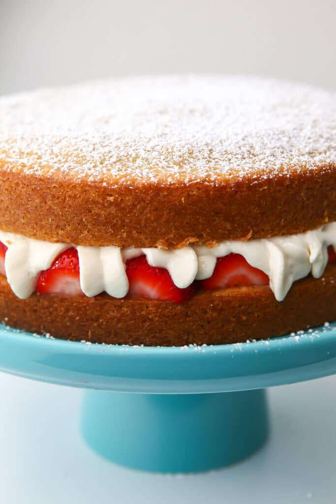 A double layer vegan sponge cake with strawberries and cream in the middle.