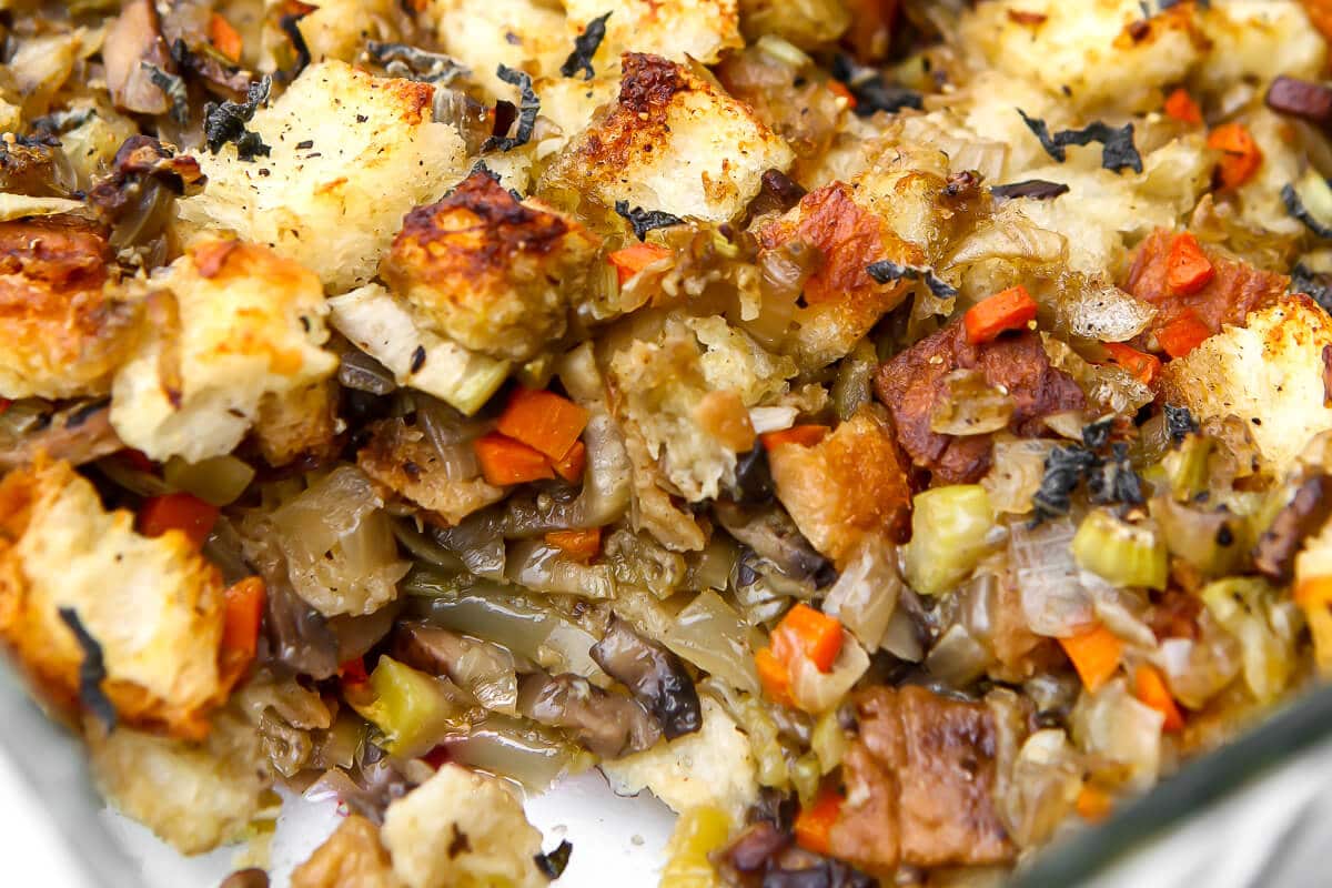A close up of baked vegan stuffing with a scoop taken out of it.