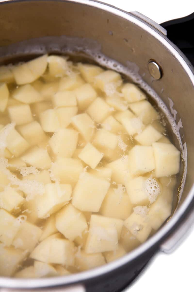 A pot full of peeled and cubed potatoes covered in water before they are cooked.