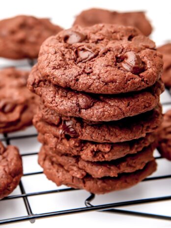 Vegan chocolate cookies on a cooling rack with a white background.