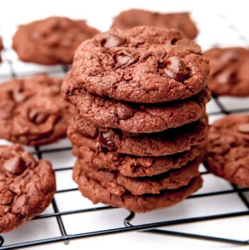 Vegan chocolate cookies on a cooling rack with a white background.