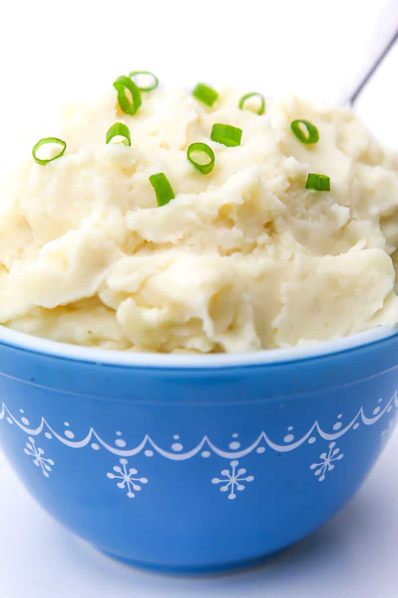 A heaping bowl of vegan mashed potatoes with chives on top.