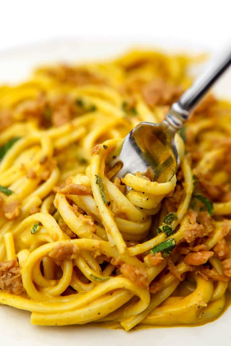 Pumpkin sauce over linguini with vegan sausage crumbles being loaded on a fork.