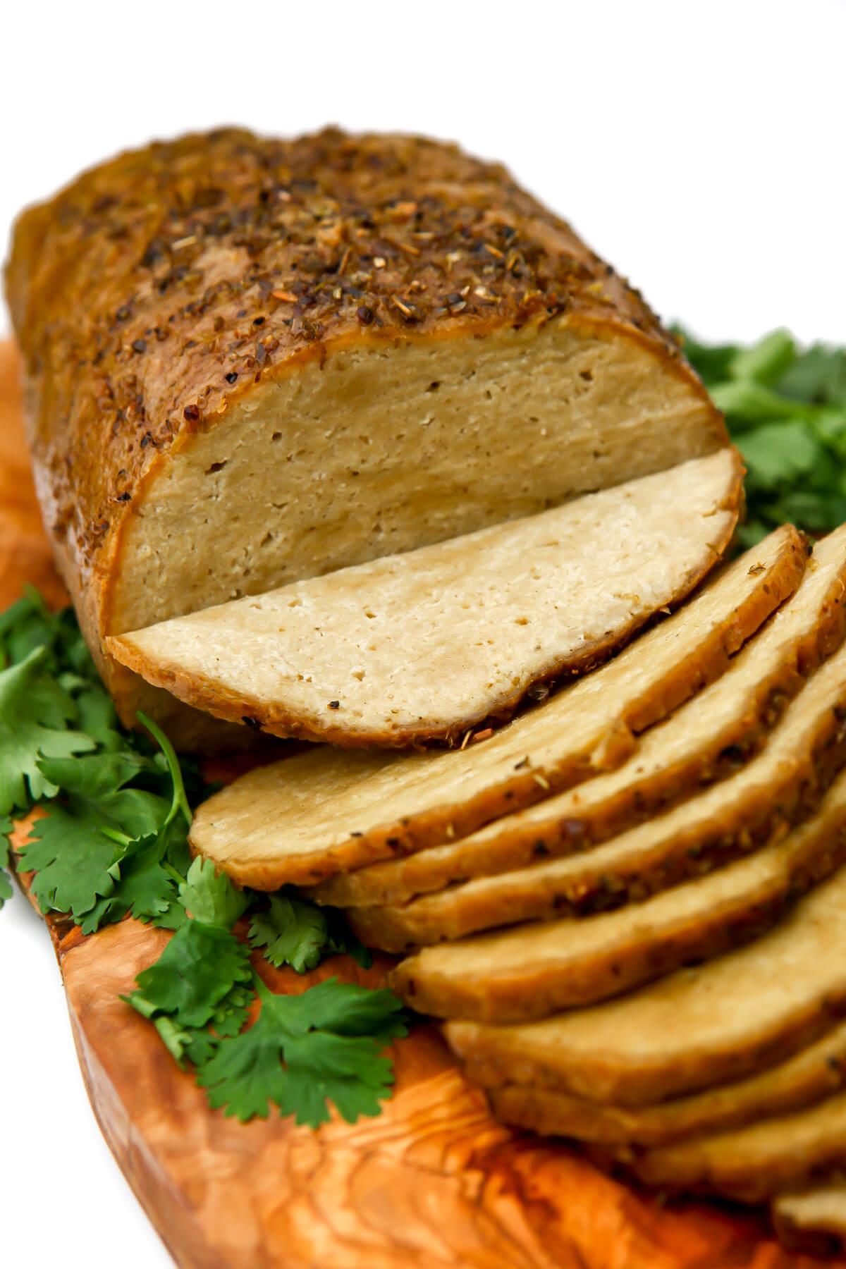 A seitan turkey on a cutting board cut into thin slices.