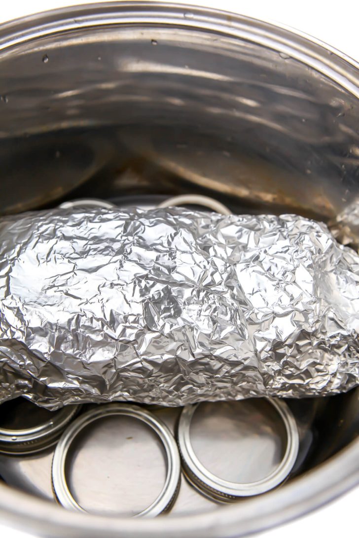 A seitan turkey loaf wrapped in foil and placed in a pot to steam.