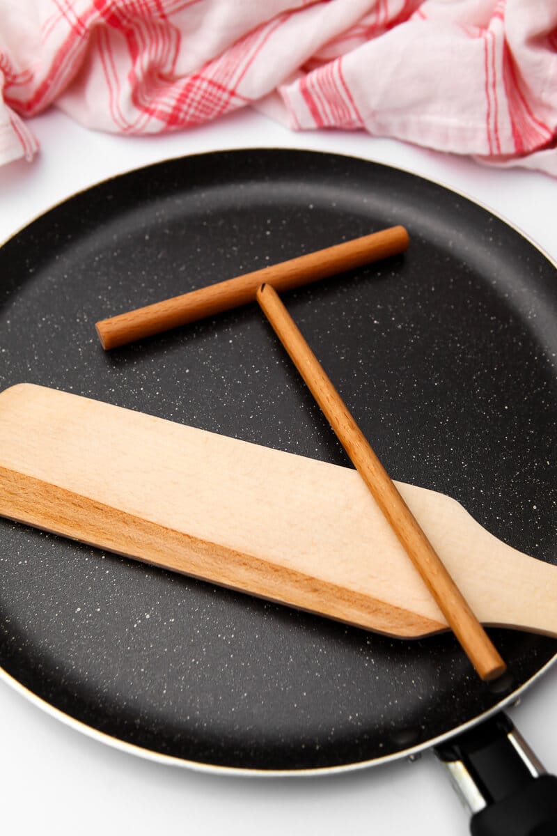 A crepe pan, crepe spreader, and wooden spatula.