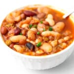 A white bowl filled with vegetarian 15 bean soup in a tomato based broth.