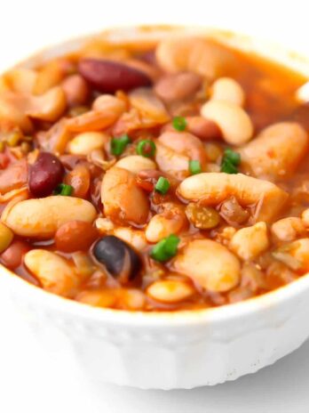 A white bowl filled with vegetarian 15 bean soup in a tomato based broth.