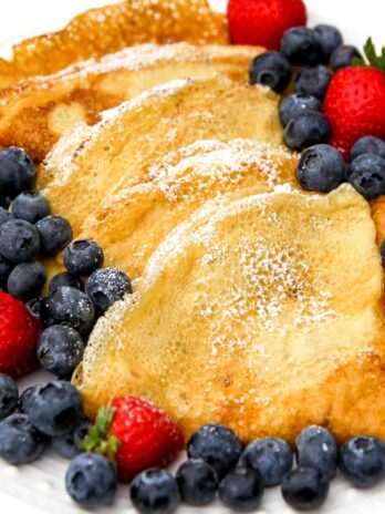Vegan crepes folded into triangles with berries on the side.
