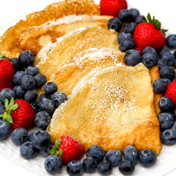 Vegan crepes folded into triangles with berries on the side.