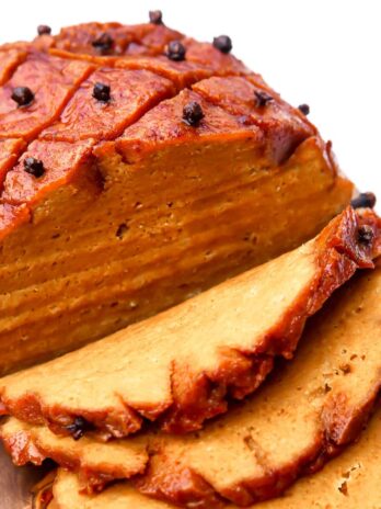 A vegan ham made from seitan sliced on a cutting board.