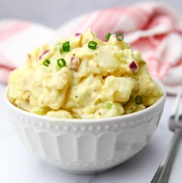 A classic vegan potato salad with red onion and chives on top.