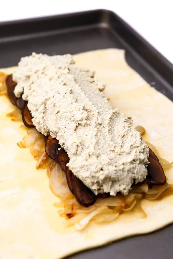 Seasoned tofu on top of carnalized onions and mushroom bacon to make a tofu wellington.