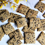 Gluten-free quinoa crackers with black sesame seeds on top.