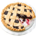 A top view of a vegan cherry pie with a slice taken out of it.