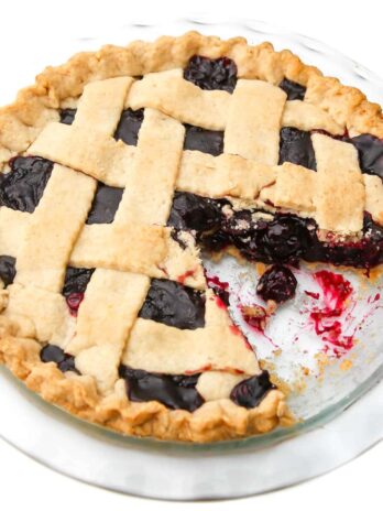 A top view of a vegan cherry pie with a slice taken out of it.