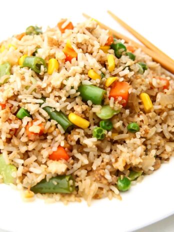 A close up of a plate of vegan fried rice with mixed veggies and tofu in it.