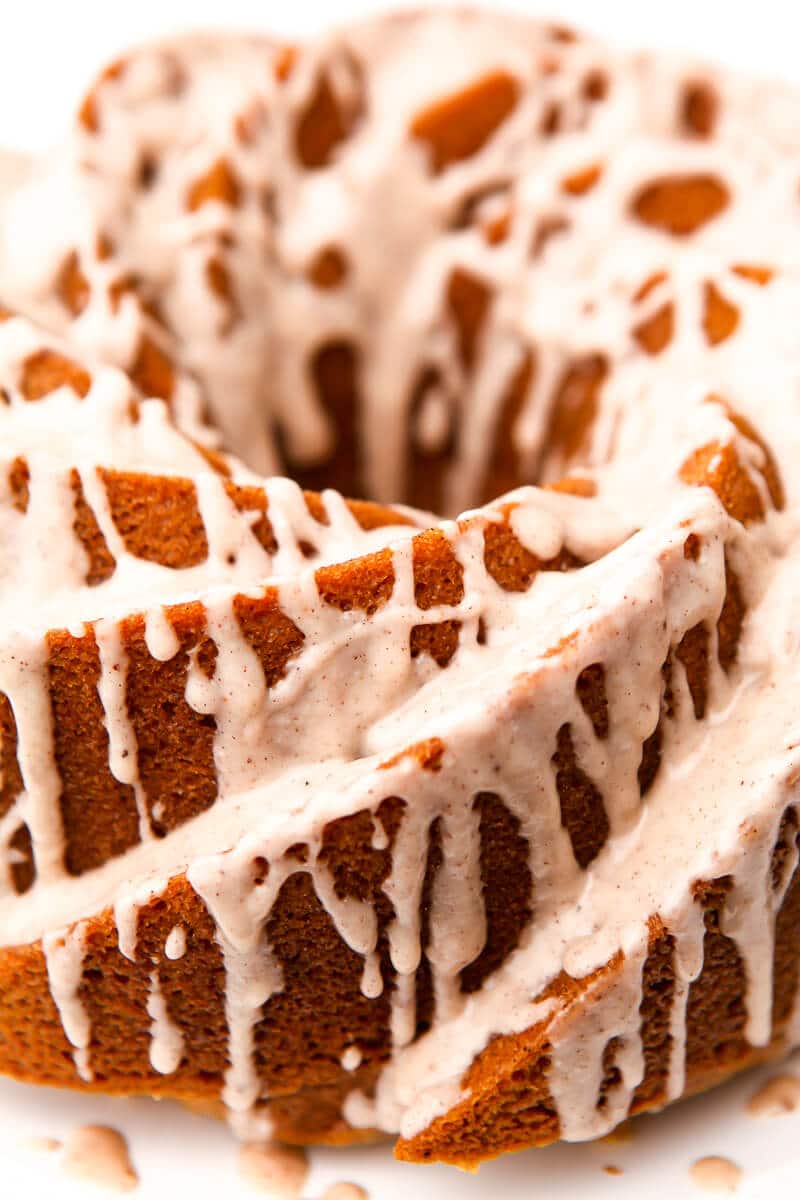 A light pink cinnamon vegan icing drizzled over top of a bundt cake.