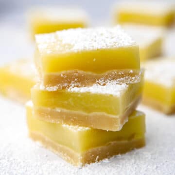 A close up of a stack of vegan lemon squares with some more behind it.