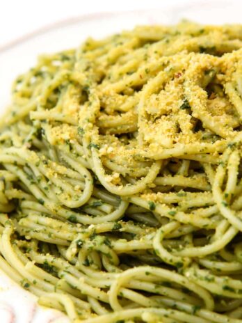 Noodles covered in vegan pesto with a fork lifting up some noodles.