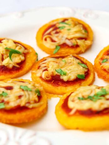 Vegan polenta pizza bites on a white plate.