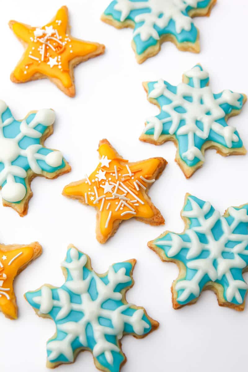 Vegan sugar cookies cut out in the shape of snowflakes and stars and decorated royal icing.