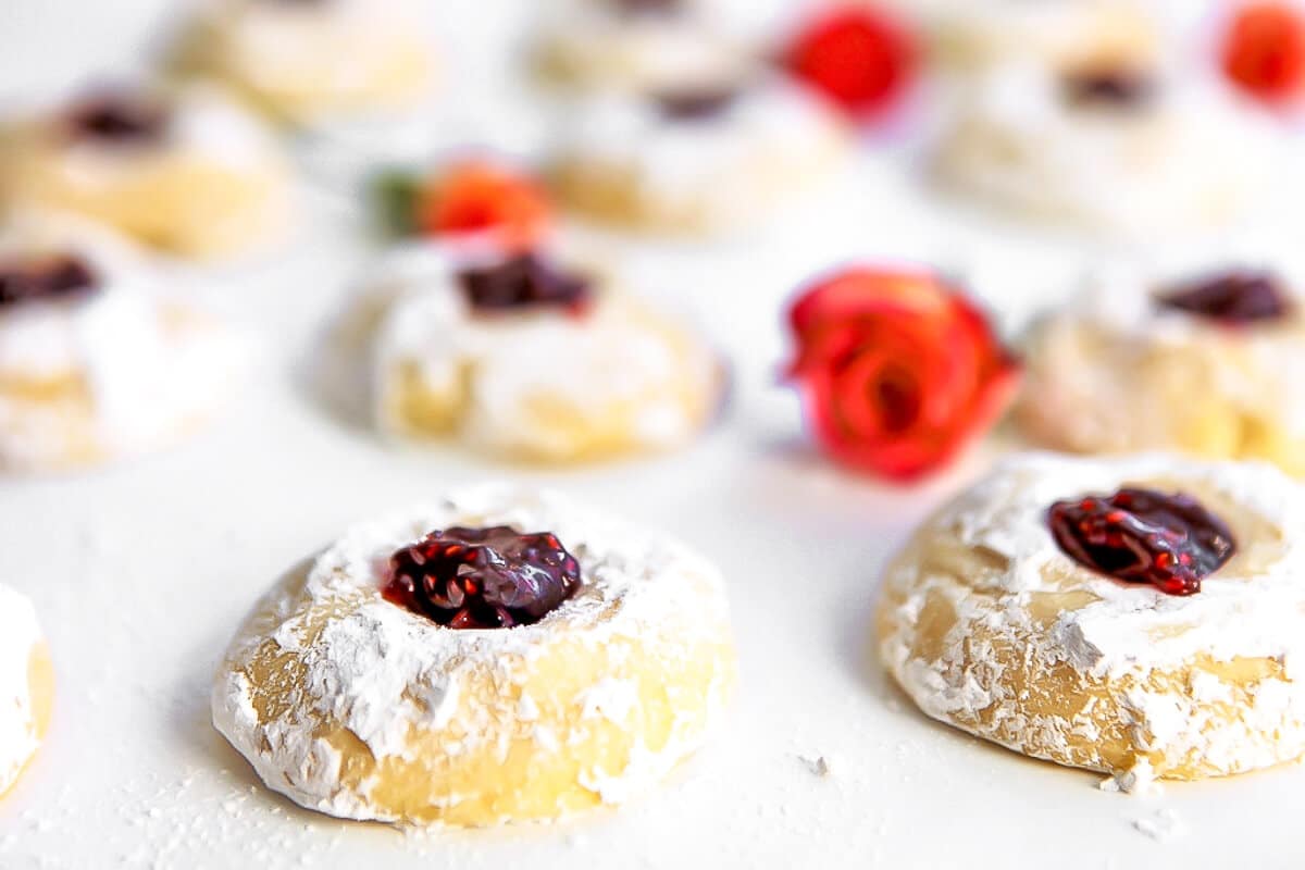 Thumbprint cookies on a white counter top with roses around them.