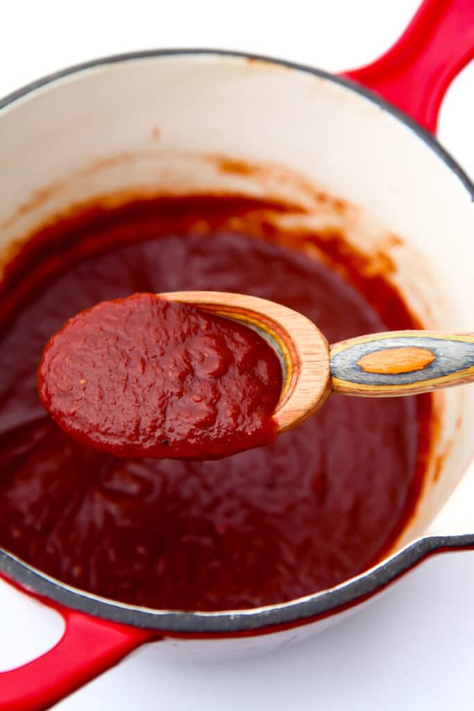A red saucepan filled with homemade vegan bbq sauce.
