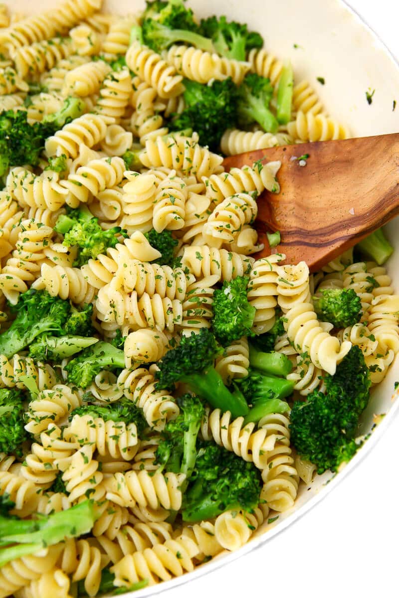 A white wok filled with broccoli pasta.